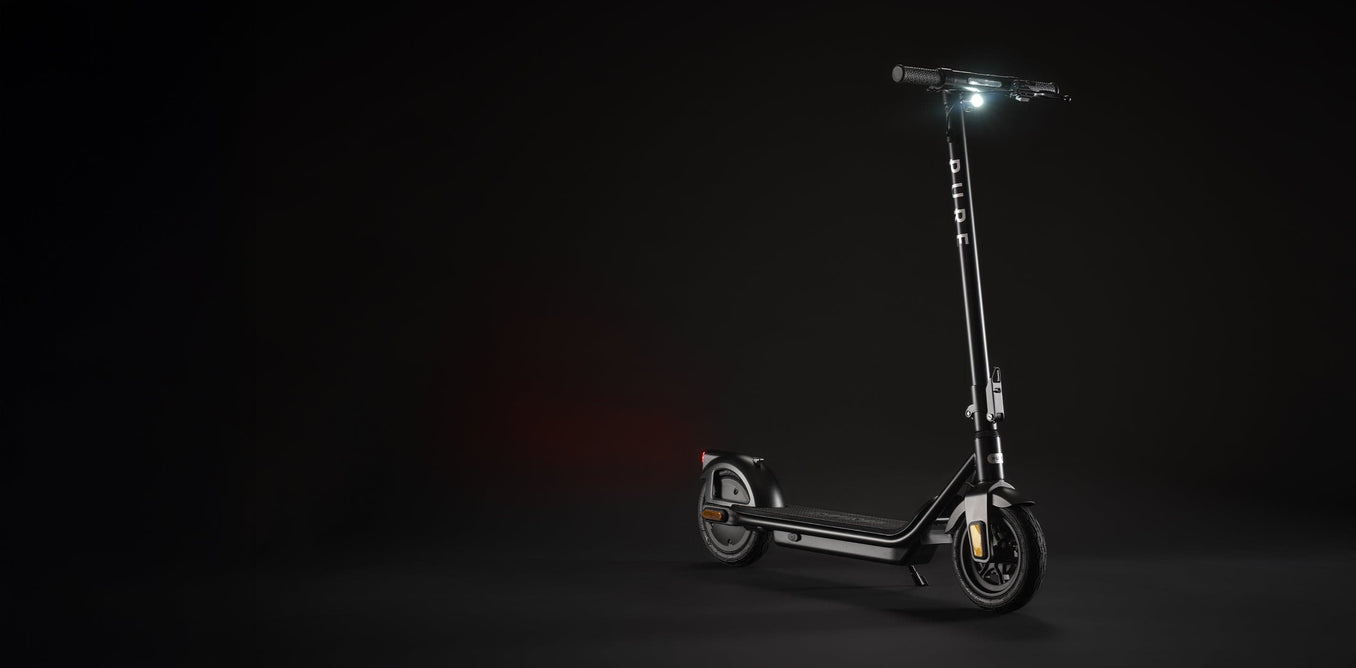 Pure Air 5 electric scooter with its headlight illuminated against a dark studio background